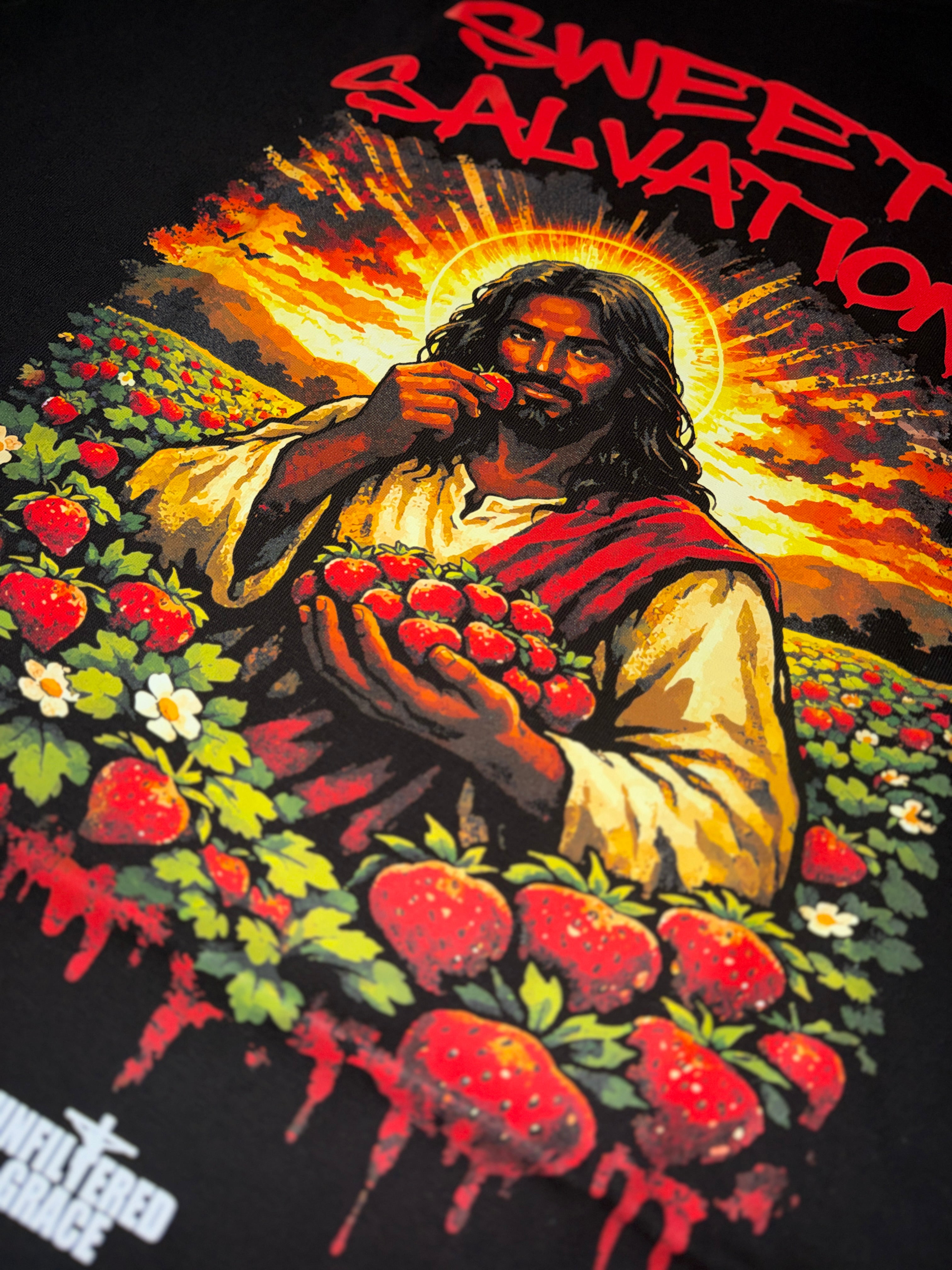 Black t-shirt design with Jesus holding strawberries in a field, titled 'Sweet Salvation'.